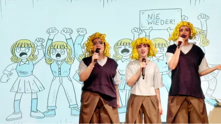 3 Menschen mit gelben Perücken im Comic-Stil, singend vor einer Grafik mit 6 Comicfiguren mit gelben Haaren. Eine der Figuren hält ein Schild mit "Nie wieder!" über den Kopf