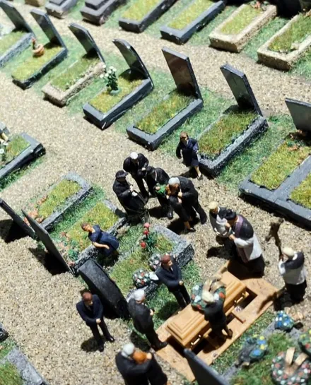 Miniaturmodell einer Beerdigung mit Trauernden um einen Sarg auf einem Friedhof mit Gräbern und Grabsteinen