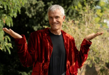 Ein Mann in roter Samtjacke steht lächelnd im Freien. © Tobias Garcia-Navas