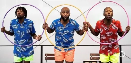 Drei Männer in Hawaiihemden mit Palmenmuster, zwei in Rot, einer in Blau, stehen nebeneinander, halten Getränke