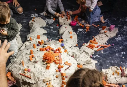 Kinder gestalten gemeinsam eine bunte Landschaft aus Ton und Spielobjekten – kreatives Chaos voller Fantasie.