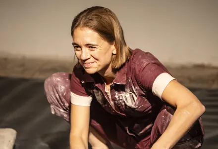 Eine Performerin formt konzentriert einen großen Tonklumpen – Kreativität in Bewegung.