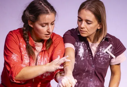 Zwei Performerinnen im Dialog, verbunden durch Gesten und Ton – ein Moment voller Achtsamkeit.