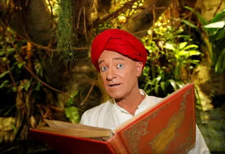 Mann mit rotem Turban liest ein rotes Buch im Dschungel.