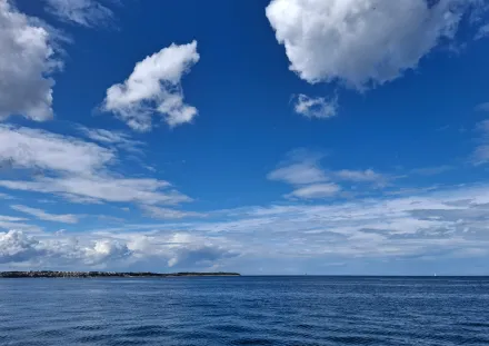 Gewässer, leicht gekräuselte Oberfläche (schwacher Wind), blauer Himmel mit Wolken